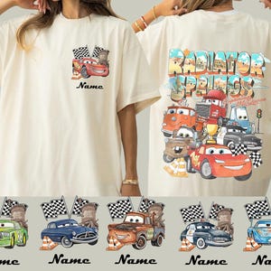 May include: Cream-colored t-shirt featuring a Cars movie design. The front displays Lightning McQueen with flags and the word "Name". The back showcases a colorful "Radiator Springs" graphic with various Cars characters. Below are five car designs with the word "Name".