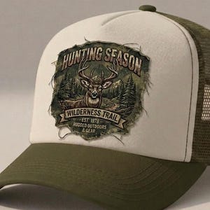 May include: A trucker hat with an olive green brim and mesh back, featuring a cream-colored front panel. A graphic patch displays a deer head, pine trees, and the text: HUNTING SEASON, WILDERNESS TRAIL, EST. 1978, RUGGED OUTDOORS & GEAR.