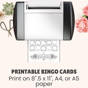 May include: A printer is shown with a printed bingo card. The card has a banner that says "BOOK BINGO" in reverse. The text at the bottom says "PRINTABLE BINGO CARDS" and "Print on 8".5 x 11", A4, or A5 paper".