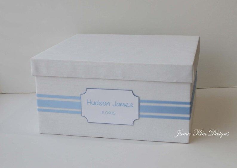 May include: White keepsake box with blue stripes and a label that reads "Hudson James 5.09.15".