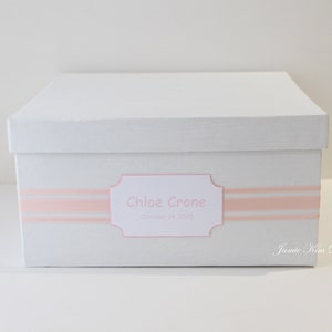 May include: White keepsake box with a pink ribbon and a label that reads "Chloe Crone, October 24, 2019".