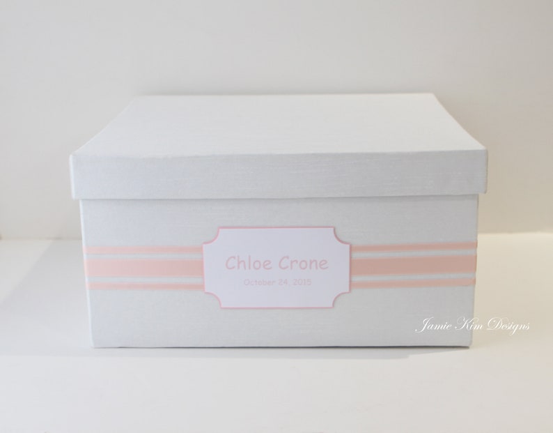 May include: White keepsake box with a pink ribbon and a label that reads "Chloe Crone, October 24, 2019".