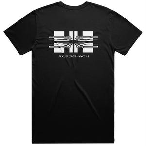 May include: Black t-shirt featuring a white and black geometric design on the back. The design includes horizontal and vertical lines, with the word "RORSCHACH" printed below the graphic in white.