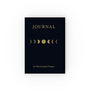 Peut inclure: Un journal bleu foncé avec des lettres dorées et un design céleste. Le mot "JOURNAL" est en haut, avec des phases de lune en dessous. Le texte "by The Cracked Teapot" est en bas.