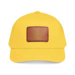May include: A bright yellow baseball cap featuring a rectangular brown leather patch centred on the front panel. The patch is stitched with black thread and displays the text Your Logo or Image Here in a subtle, embossed-style font.