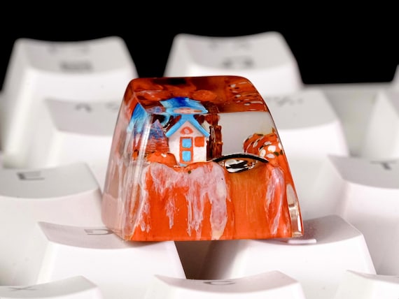 Hand-cast resin keycaps shaped like tiny cottages — a miniature landscape living on your mechanical keyboard that nobody else in the office will have.
