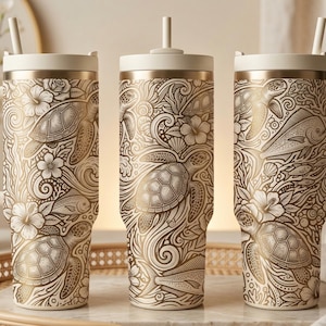 May include: Three insulated tumblers with handles and straws. The tumblers feature a cream-colored base with a detailed gold design of sea turtles, fish, and flowers. The lids and handles are a matching cream color, creating a cohesive aesthetic.