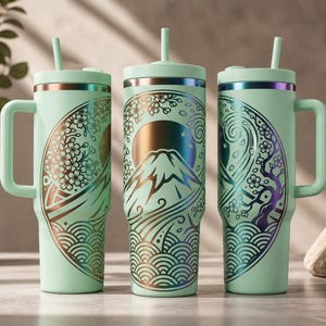 May include: Three mint-green insulated tumblers with handles and straws. Each tumbler features a Japanese-inspired design with Mount Fuji, cherry blossoms, and waves in gold and iridescent accents. The tumblers are designed for cold beverages.