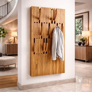 May include: A wooden wall-mounted coat rack with multiple hooks. The rack is made of vertical wooden slats with integrated hooks. A light gray jacket hangs from one of the hooks. The wood has a natural finish.