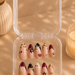 Pu&ograve; includere: Un set di unghie finte a forma di mandorla in una custodia di plastica trasparente. Le unghie sono decorate con vari disegni, tra cui pois, stelle e labbra, nelle tonalit&agrave; nude, bordeaux e nero. Alcune unghie hanno accenti dorati.