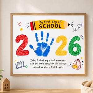 Può includere: Una stampa da parete rettangolare con una matita gialla e il testo My first day of SCHOOL. Il design include un'impronta di mano blu tra i numeri 2 e 26, con un libro, uno zaino e stelle. Il testo recita: Today I start my school adventure, and this little handprint will always remind us where it all began.