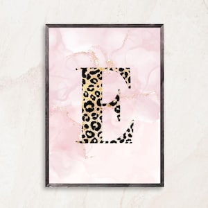 May include: Framed art print featuring the letter "E" in a leopard print design. The letter is set against a pink and gold abstract background. The frame is dark brown.