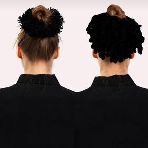 May include: Two people are seen from the back, each wearing a black blazer. One has their hair up in a bun with a black, fluffy hair accessory. The other has a similar accessory, but with their hair down. The background is plain white.
