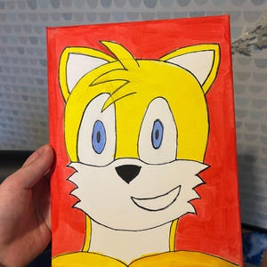 Può includere: Una tela dipinta a mano raffigurante Tails della serie Sonic the Hedgehog. L'opera mostra la pelliccia gialla di Tails, gli occhi blu e il muso bianco su uno sfondo rosso acceso. La tela è di forma rettangolare.