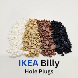 May include: Four piles of IKEA Billy hole plugs in white, beige, brown, and black. The plugs are small, cylindrical, and have a flat, circular top. The text "IKEA Billy Hole Plugs" is displayed in blue and black.
