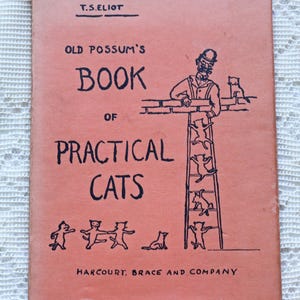 May include: A pink hardcover book titled Old Possum's Book of Practical Cats by T.S. Eliot, published by Harcourt, Brace and Company. The cover features black line illustrations of a person in a hat and multiple cats on a ladder and ground.