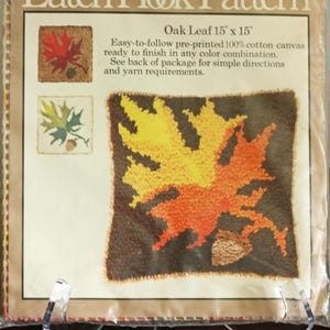 May include: A Caron Latch Hook Pattern kit for an Oak Leaf design measuring 15 inches by 15 inches. The packaging features text, two small color variations of the leaf, and a large central image of a yellow and orange leaf on a brown background.