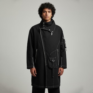 Könnte beinhalten: Schwarzer Mantel mit hohem Kragen und asymmetrischem Reißverschluss. Der Mantel hat weiße Nähte, mehrere Taschen und ein einzigartiges Design. Das Model trägt den Mantel und präsentiert seine moderne und stilvolle Ästhetik.