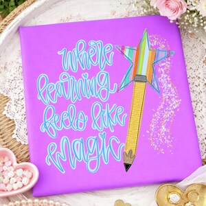 May include: A square purple sign featuring the light blue cursive text Where learning feels like magic. To the right is a yellow pencil with a multi-colored striped star topper and a trail of gold glitter sparkles extending downward.
