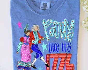 May include: A blue Comfort Colors t-shirt featuring a graphic of two people in colonial attire with the text "Party Like It's 1776". The design includes red stars and stripes, and a pink star.