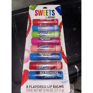 Puede incluir: Un paquete de ocho bálsamos labiales con sabor de Hershey. Los bálsamos labiales son de varios colores, incluyendo rojo, azul, verde y rosa. El paquete tiene el texto "SWEETS by Hershey" y "8 Flavored Lip Balms". El peso neto total es de 27,2 g.