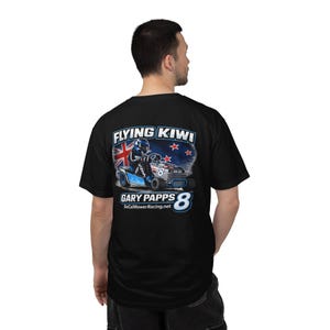 May include: Black t-shirt featuring a graphic of a lawnmower racer with the text "FLYING KIWI" and "GARY PAPPS 8". The design includes the New Zealand flag and stars. The SoCalMowerRacing.net website is also displayed.