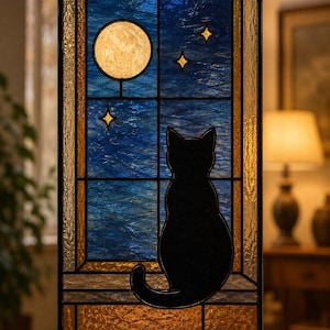 May include: Stained glass window panel featuring a black cat silhouette gazing at a moon and stars. The window has a blue and gold color scheme, with a textured appearance. The panel is framed in black and hangs from a chain.