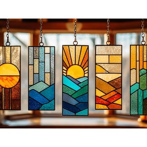 Könnte beinhalten: Fünf rechteckige Buntglasscheiben, die an Ketten hängen. Jedes Paneel zeigt ein anderes Landschaftsmotiv, darunter ein Sonnenaufgang, Berge und abstrakte geometrische Muster. Die Paneele verwenden eine Vielzahl von Farben, darunter Gelb, Orange, Blau und Grün.