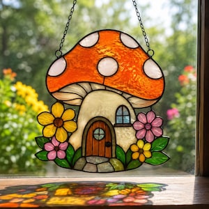 May include: Stained glass mushroom house with an orange cap and white polka dots. The house has a wooden door, a small window, and is surrounded by colorful flowers. It hangs from a black chain.