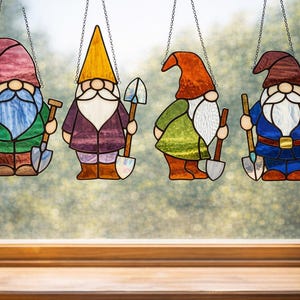 May include: Four stained glass garden gnome ornaments hanging in front of a window. Each gnome has a different colored hat and outfit, and holds a shovel. The gnomes are in shades of red, purple, yellow, green, and blue.