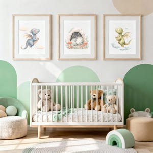 May include: Three framed watercolor prints of baby dragons in a nursery setting. One print shows a blue dragon flying, another depicts a dragon in a cave, and the third shows a green dragon. A white crib with teddy bears is in the foreground.