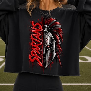 Peut inclure: Un sweat-shirt court noir avec une impression graphique représentant un casque spartiate doté d'un panache rouge et d'yeux rouges brillants. Le mot SPARTANS est écrit en lettres rouges stylisées à gauche du casque, avec des éclaboussures rouges.