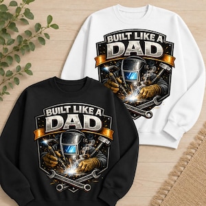 May include: A white and a black sweatshirt, each featuring a graphic of a welder wearing a helmet and gloves, holding a welding torch with sparks. The design includes crossed wrenches and the text BUILT LIKE A DAD in a shield-shaped emblem.