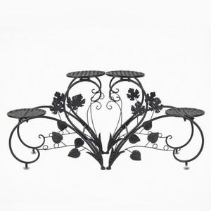 May include: Black metal plant stand with four circular platforms and decorative leaf and vine accents. The stand has a scrolled design and is suitable for displaying multiple potted plants. The platforms are approximately 8 inches in diameter.