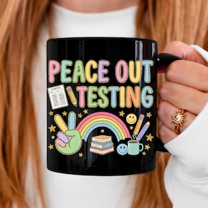 Op de afbeelding: Een witte keramische mok met een zwart handvat en de tekst "But First, Coffee" in een vetgedrukte, zwarte letter. De mok staat tegen een vage achtergrond. De mok is ongeveer 10 cm hoog.