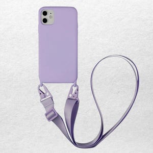 May include: A lavender phone case with a matching lanyard. The case has a smooth finish and is attached to the lanyard with silver-colored metal clips. The lanyard is made of a soft, woven material.