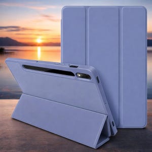 Puede incluir: Dos fundas para tabletas de color azul-violeta, una abierta y apoyada, la otra cerrada. La funda abierta está en ángulo, revelando el borde de la tableta. El fondo muestra una puesta de sol sobre el agua.