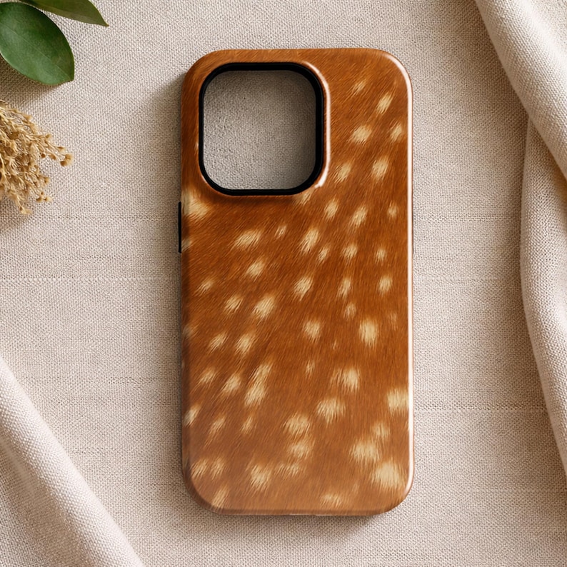 May include: A brown and tan phone case with a deer fur pattern. The case has a black camera cutout and a glossy finish. The case is rectangular with rounded corners.