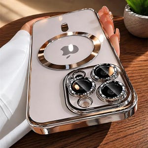 May include: Clear iPhone case with a gold-colored frame and accents. The case features a gold ring around the Apple logo and a protective frame around the camera lenses. The case is designed to protect the phone.
