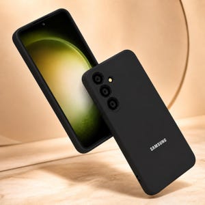 May include: Black phone case and smartphone. The phone case has a matte finish and a camera cutout. The smartphone screen displays a green and yellow gradient. The Samsung logo is visible on the phone case.