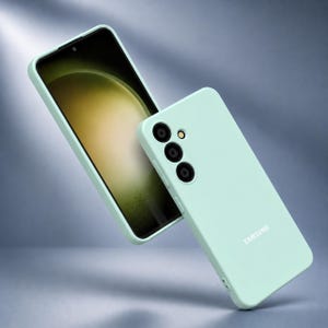 May include: A mint green phone case and a smartphone with a black screen. The phone case has three camera lenses and the word "SAMSUNG" printed on it. The phone screen displays a light green and yellow gradient.
