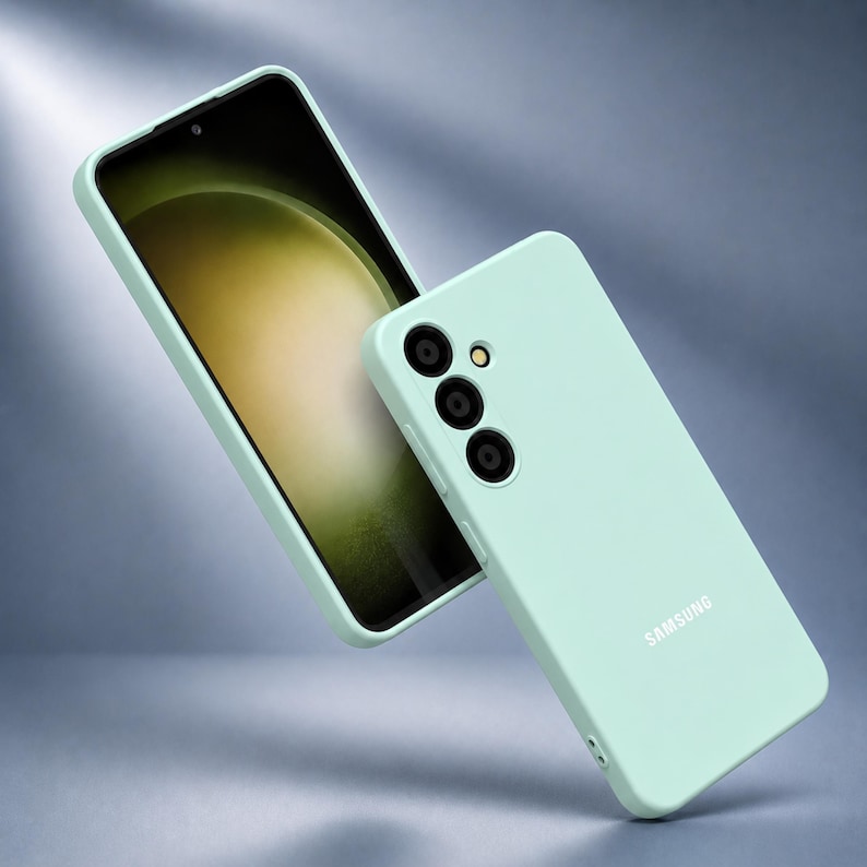 May include: A mint green phone case and a smartphone with a black screen. The phone case has three camera lenses and the word "SAMSUNG" printed on it. The phone screen displays a light green and yellow gradient.