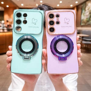 May include: Two phone cases, one mint green and one lavender, are held up. Each case has a camera ring, a heart graphic, and the text "Smile every day." The camera rings have the text "KATHY TECH" and "Quality makes the future."