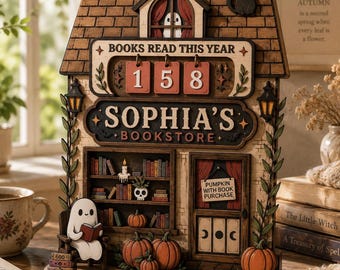 May include: A wooden bookstore display with the name "Sophia's Bookstore" and the number "158" displayed. The display features a ghost reading a book, pumpkins, and a black cat. The sign reads "Pumpkin with book purchase."