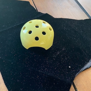 May include: A yellow plastic dome with multiple holes, possibly used for plant propagation or as a decorative object.