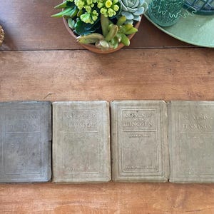 May include: Four vintage books with titles including "An Evening with Dickens," "An Evening with Shakspere," "An Evening with Lincoln," and "An Evening with Tennyson." The books are arranged on a wooden surface.