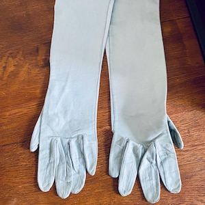 May include: A pair of long, light blue leather gloves. The gloves are fully extended and the fingers are spread out.