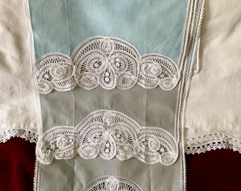 May include: Pale blue and white lace handkerchiefs. The handkerchiefs have a delicate, intricate white lace border. The fabric is a soft, light blue color. The lace design features floral and scroll patterns. The handkerchiefs are folded and layered.