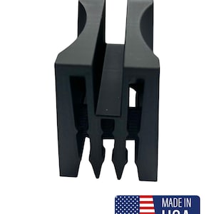 Puede incluir: Un objeto metálico negro con un diseño en forma de U, con ranuras verticales y tres puntas en la base. El objeto tiene un acabado mate y está sobre un fondo blanco. Una etiqueta "MADE IN USA" está en la esquina inferior derecha.