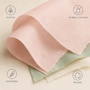 May include: Sheets of soft, pliable tissue paper in shades of pale pink, muted green, and off-white. The paper is labeled as acid-free, no bleed, color-fast, and recycled, with icons indicating these features printed around the paper sheets.
